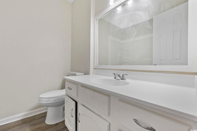 bathroom with baseboards, vanity, toilet, and wood finished floors