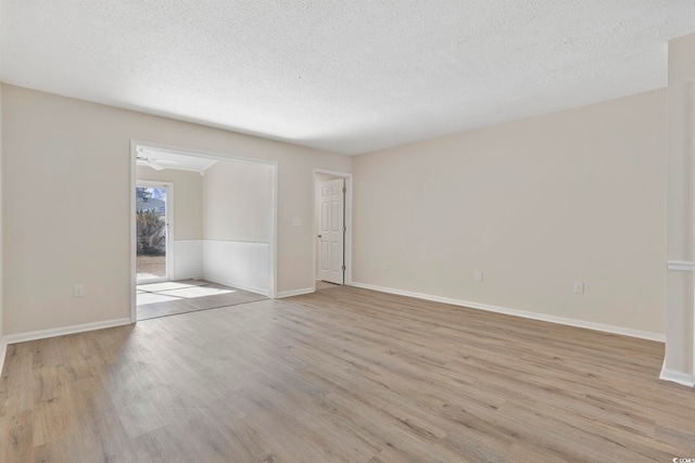 empty room with light wood-type flooring, a textured ceiling, and baseboards