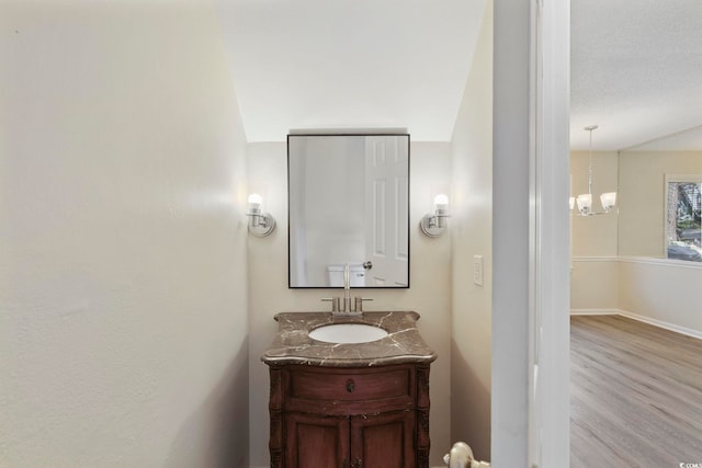 bathroom with a chandelier, wood finished floors, vanity, and baseboards