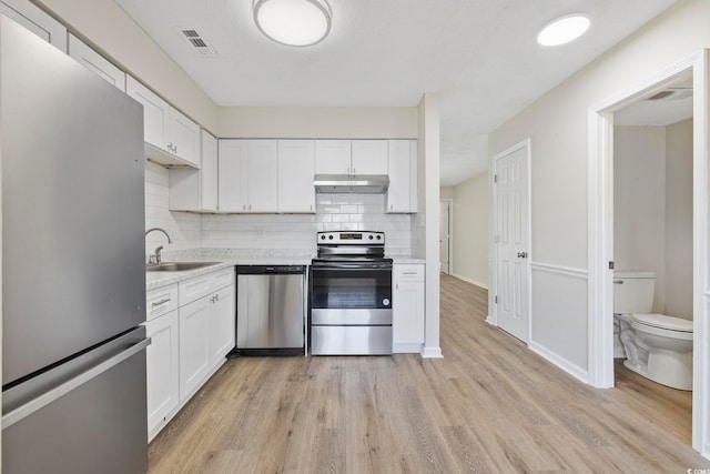 kitchen with appliances with stainless steel finishes, visible vents, under cabinet range hood, and white cabinetry