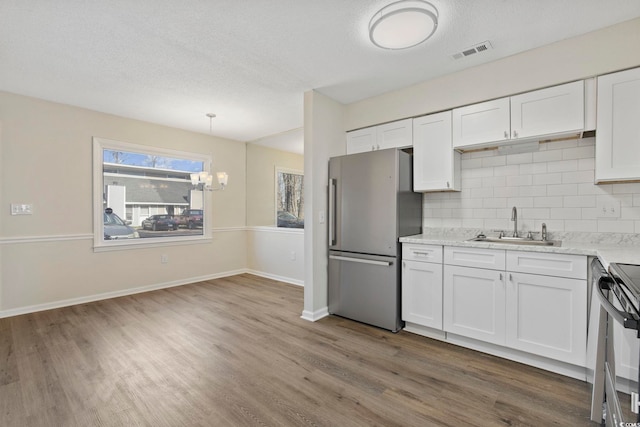 kitchen featuring stainless steel appliances, tasteful backsplash, a sink, and white cabinetry