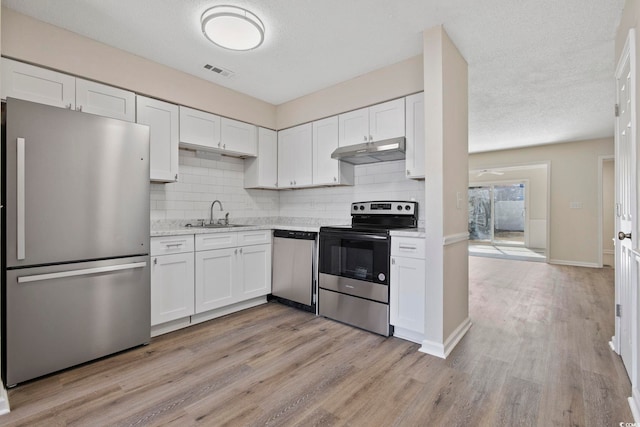 kitchen with appliances with stainless steel finishes, white cabinets, a sink, and under cabinet range hood