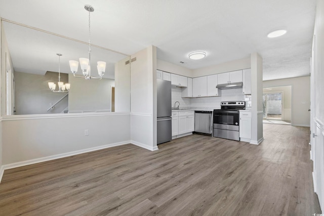 kitchen featuring tasteful backsplash, stainless steel appliances, light wood-type flooring, white cabinetry, and a notable chandelier