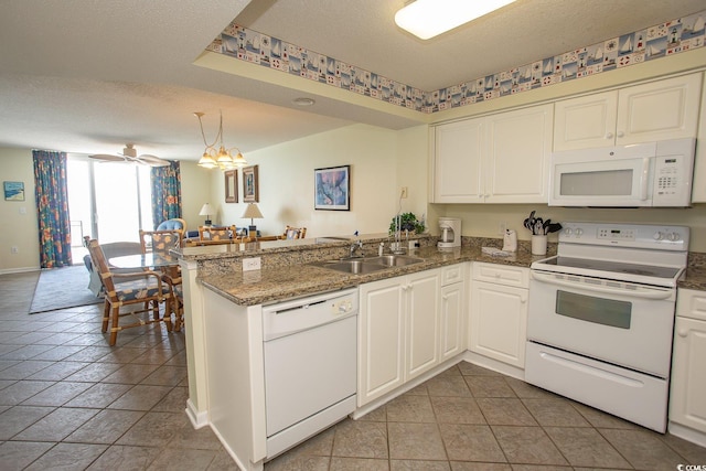 kitchen featuring open floor plan, a sink, a textured ceiling, white appliances, and a peninsula