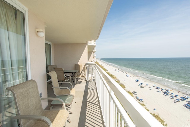 balcony featuring a view of the beach and a water view