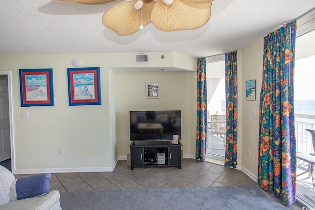 living room featuring baseboards, tile patterned flooring, visible vents, and a textured ceiling