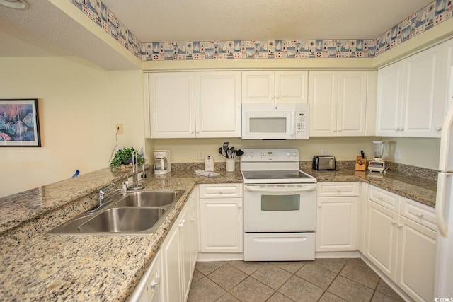 kitchen with white appliances, white cabinets, a sink, and light tile patterned floors