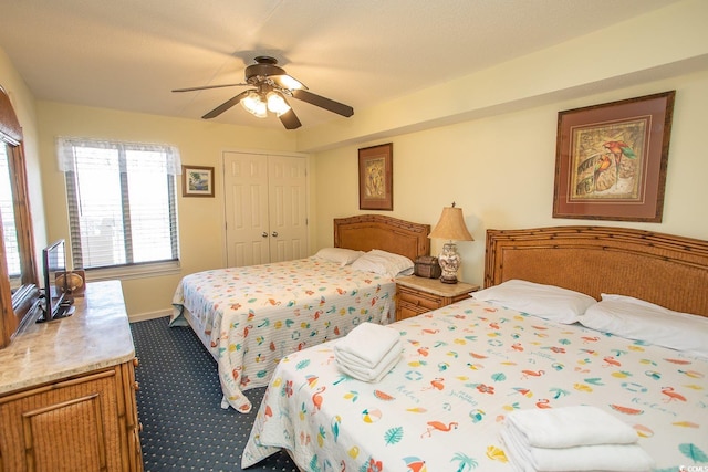 bedroom with a ceiling fan, dark colored carpet, a closet, and baseboards