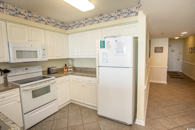 kitchen with light tile patterned floors, a textured ceiling, white appliances, baseboards, and dark countertops