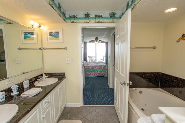 bathroom with baseboards, connected bathroom, a tub with jets, a textured ceiling, and vanity