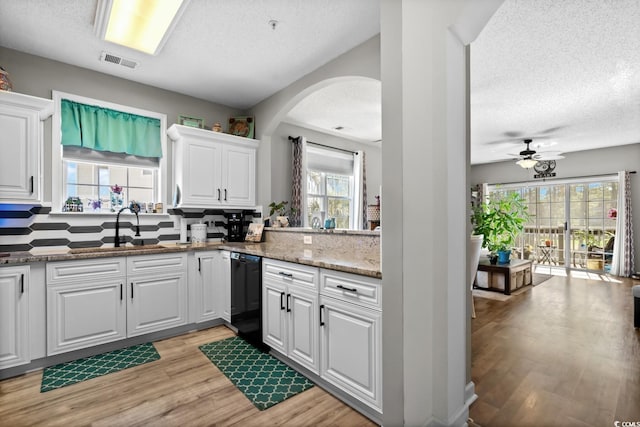 kitchen featuring visible vents, light wood-style flooring, white cabinets, a sink, and dishwasher