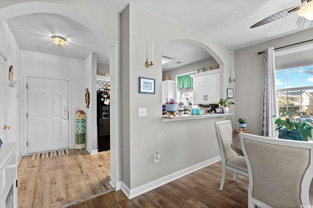 entryway featuring a ceiling fan, a textured ceiling, baseboards, and wood finished floors