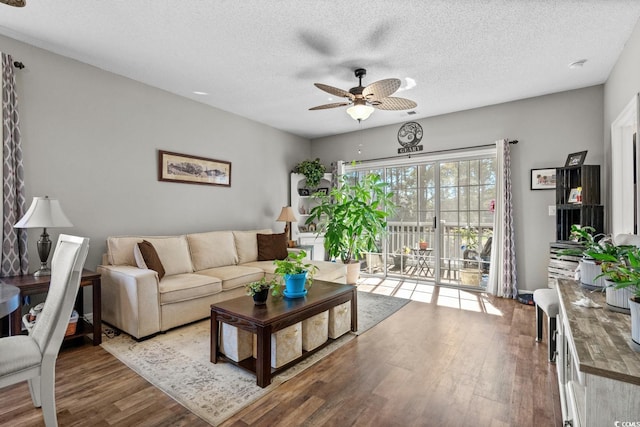 living area with a ceiling fan, a textured ceiling, and wood finished floors