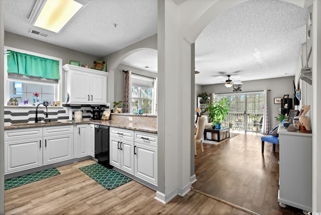 kitchen featuring light wood-style flooring, visible vents, white cabinets, and dishwasher