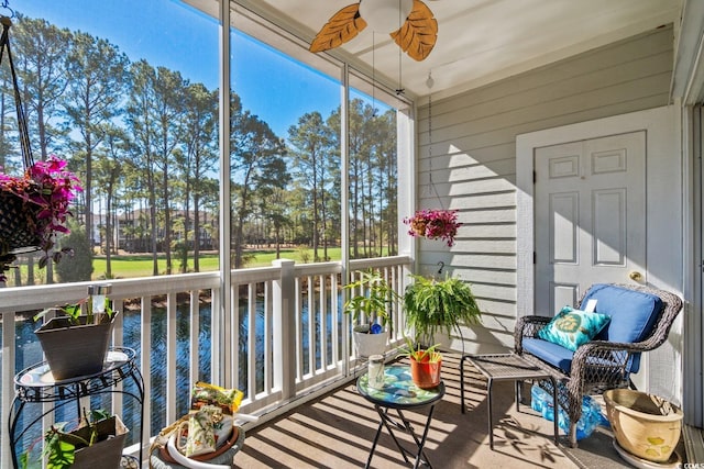 sunroom featuring ceiling fan and a water view