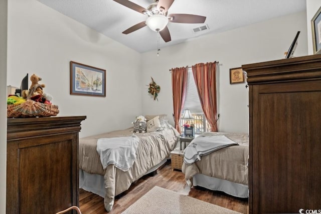 bedroom with a ceiling fan, visible vents, and wood finished floors