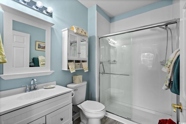 full bathroom featuring a shower stall, toilet, and vanity