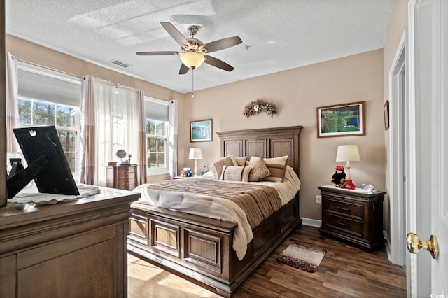 bedroom with a ceiling fan, visible vents, a textured ceiling, and wood finished floors