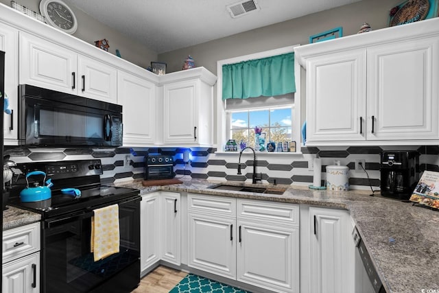 kitchen featuring visible vents, white cabinets, a sink, black appliances, and backsplash