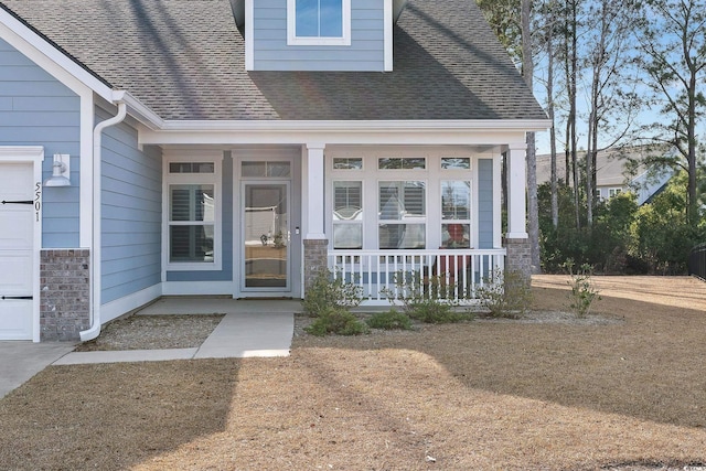 entrance to property featuring stone siding, a shingled roof, and a porch