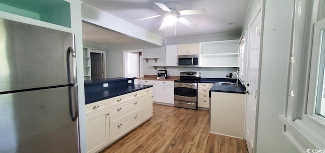 kitchen with dark countertops, stainless steel appliances, white cabinetry, open shelves, and a sink