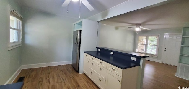 kitchen featuring dark wood-type flooring, dark countertops, freestanding refrigerator, and white cabinets