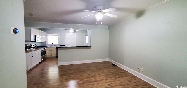 kitchen featuring stainless steel appliances, dark countertops, dark wood-type flooring, ceiling fan, and baseboards