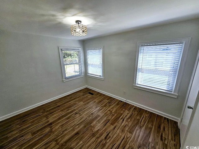 empty room with visible vents, baseboards, and dark wood finished floors