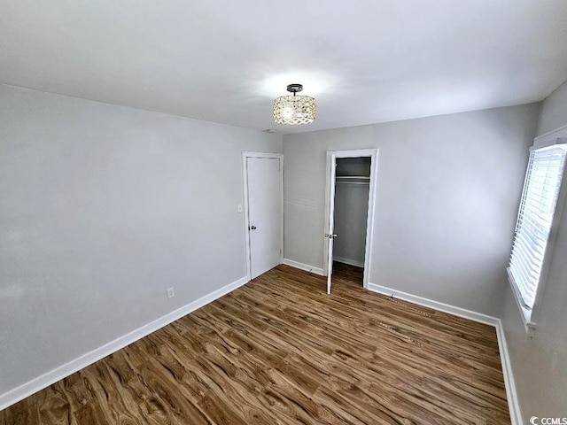 unfurnished bedroom featuring dark wood-style floors, baseboards, and a closet