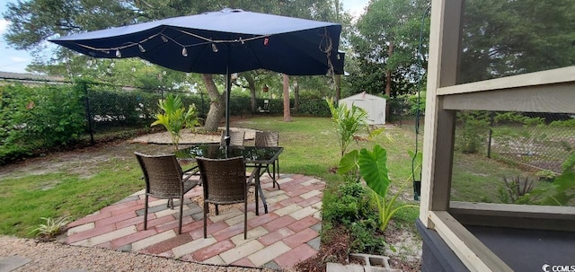 view of patio / terrace featuring an outbuilding, outdoor dining area, a fenced backyard, and a storage shed