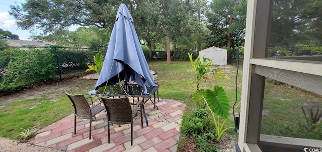 view of patio with a fenced backyard, outdoor dining area, and an outbuilding