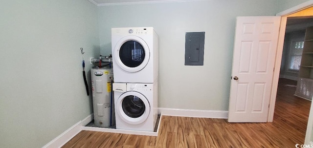 laundry area with electric water heater, stacked washing maching and dryer, wood finished floors, electric panel, and baseboards