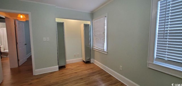 unfurnished bedroom featuring baseboards, wood finished floors, and crown molding