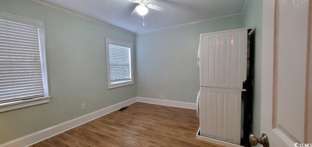 spare room with ceiling fan, baseboards, crown molding, and wood finished floors