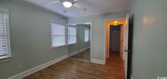 unfurnished bedroom featuring crown molding, a closet, a ceiling fan, wood finished floors, and baseboards