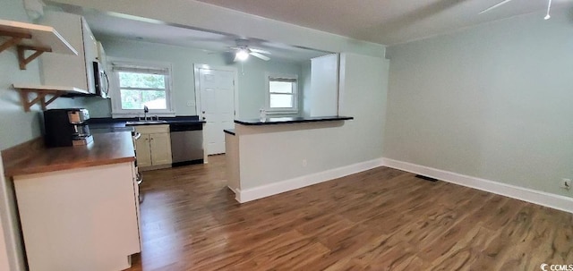 kitchen with dark wood-style floors, open shelves, dark countertops, appliances with stainless steel finishes, and baseboards