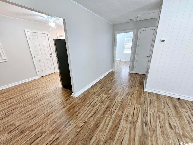 empty room with ornamental molding, light wood-style flooring, and baseboards