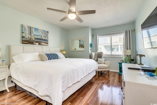 bedroom featuring ceiling fan, a textured ceiling, baseboards, and wood finished floors