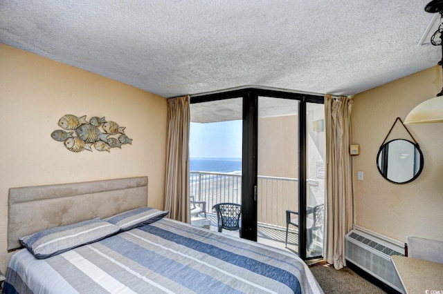 carpeted bedroom featuring a textured ceiling, a wall unit AC, a water view, access to exterior, and a wall of windows