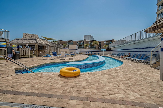 community pool with a patio area and fence