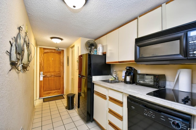 kitchen featuring a textured ceiling, a sink, white cabinets, light countertops, and black appliances