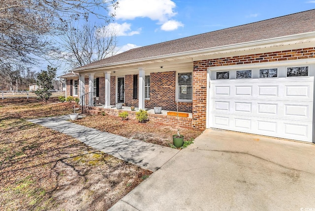 ranch-style house featuring an attached garage, driveway, a porch, and brick siding