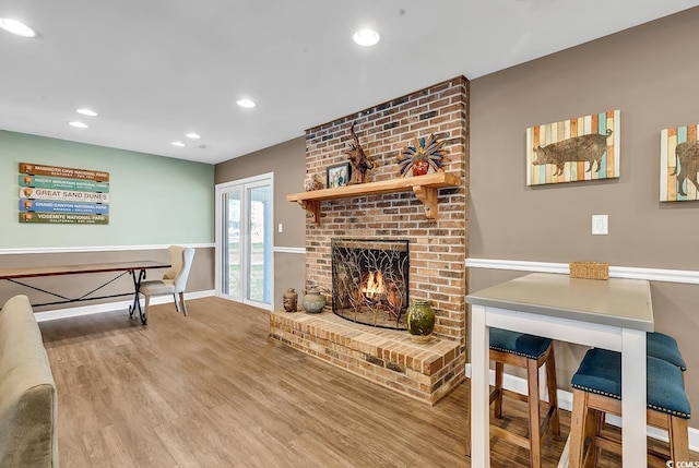 living room featuring recessed lighting, a fireplace, baseboards, and wood finished floors