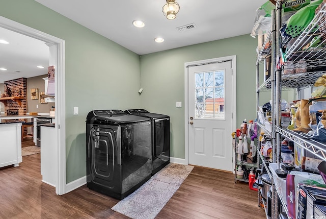 clothes washing area featuring washing machine and dryer, laundry area, dark wood-type flooring, visible vents, and baseboards