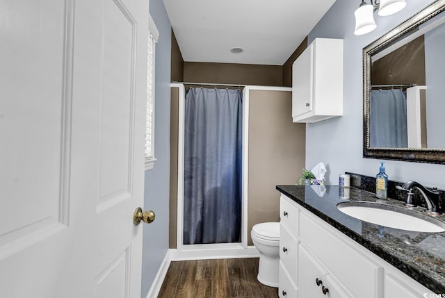 bathroom featuring a shower with shower curtain, toilet, vanity, wood finished floors, and baseboards