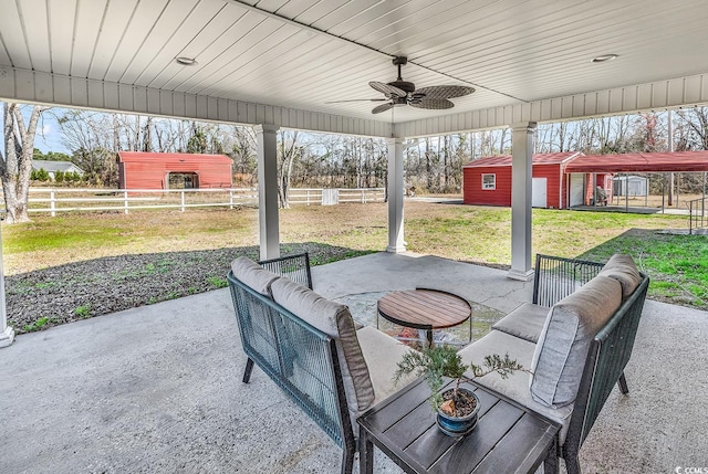 view of patio with a ceiling fan, an outbuilding, outdoor lounge area, and fence