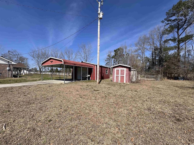 exterior space featuring a storage shed, an outdoor structure, fence, driveway, and a detached carport