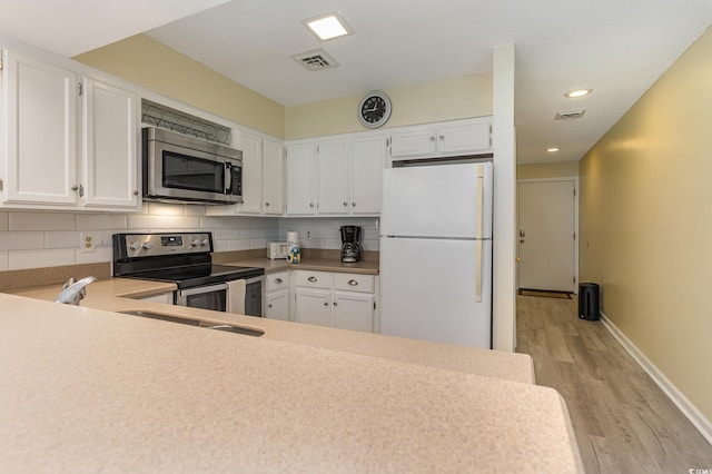 kitchen with visible vents, tasteful backsplash, light wood-style floors, appliances with stainless steel finishes, and white cabinets