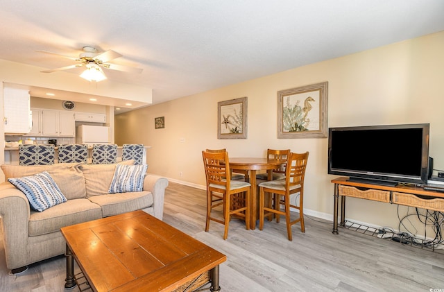 living area featuring light wood-type flooring, baseboards, and a ceiling fan