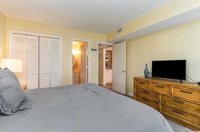 bedroom with baseboards, visible vents, a closet, and connected bathroom